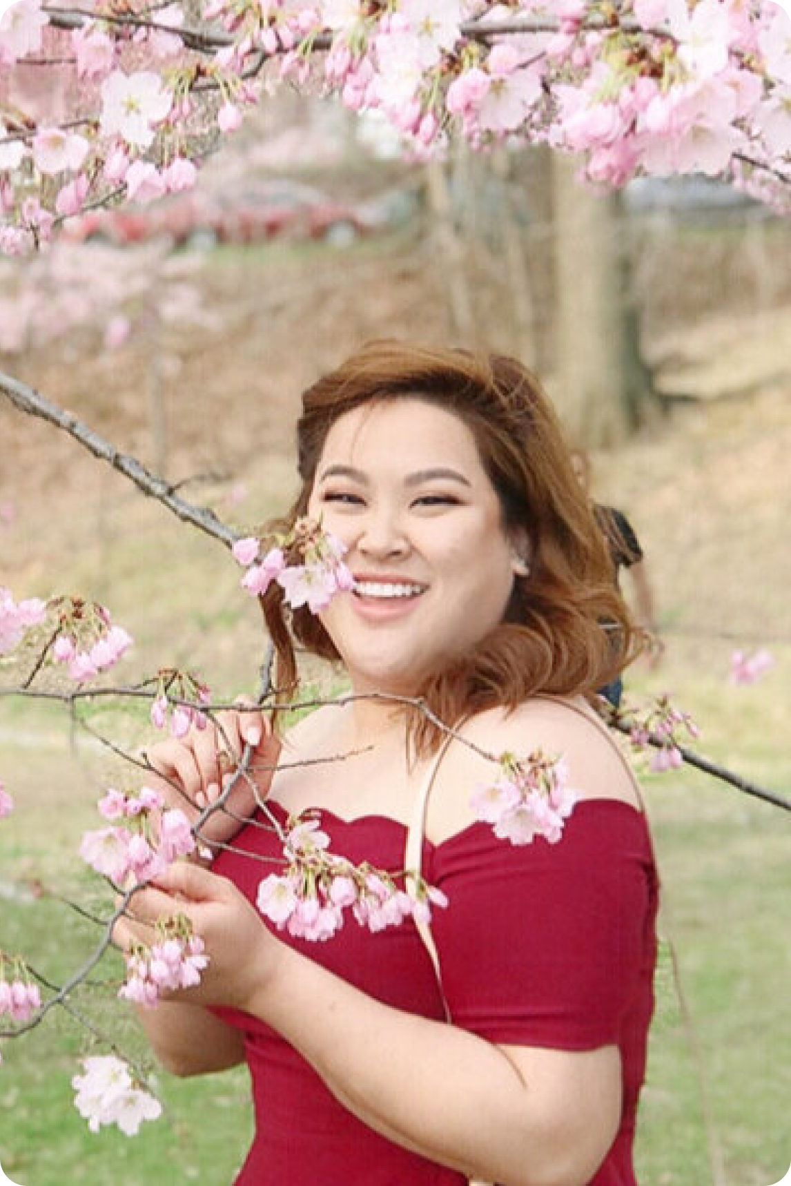 Eva Lynn Cheung standing under a cherry blossom tree in bloom.